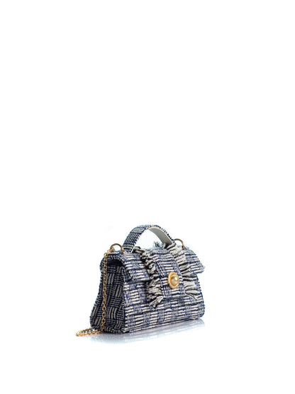 Side view of the KOORELOO Noble Mini in navy and ivory tweed with geometric woven pattern, fringed front detailing, top handle, signature gold-tone closure and chain strap
