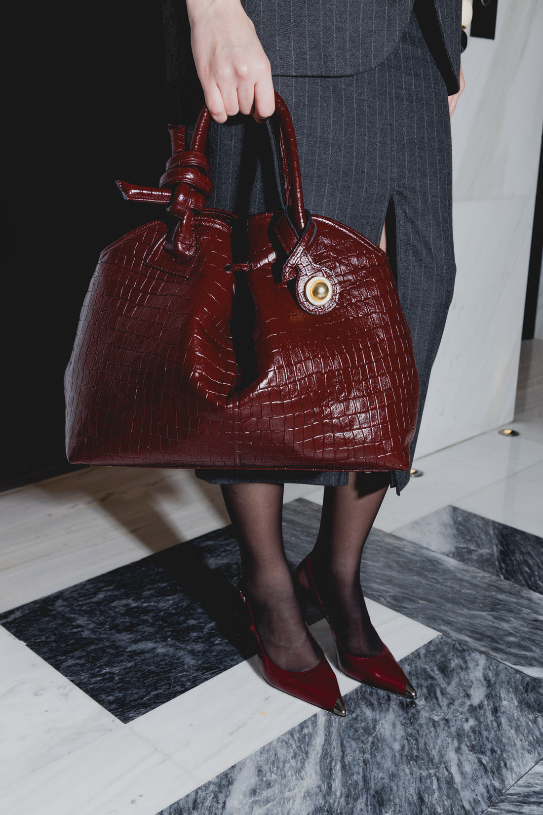 Woman carrying KOORELOO Swan 2.0 Maxi bordeaux leather handbag